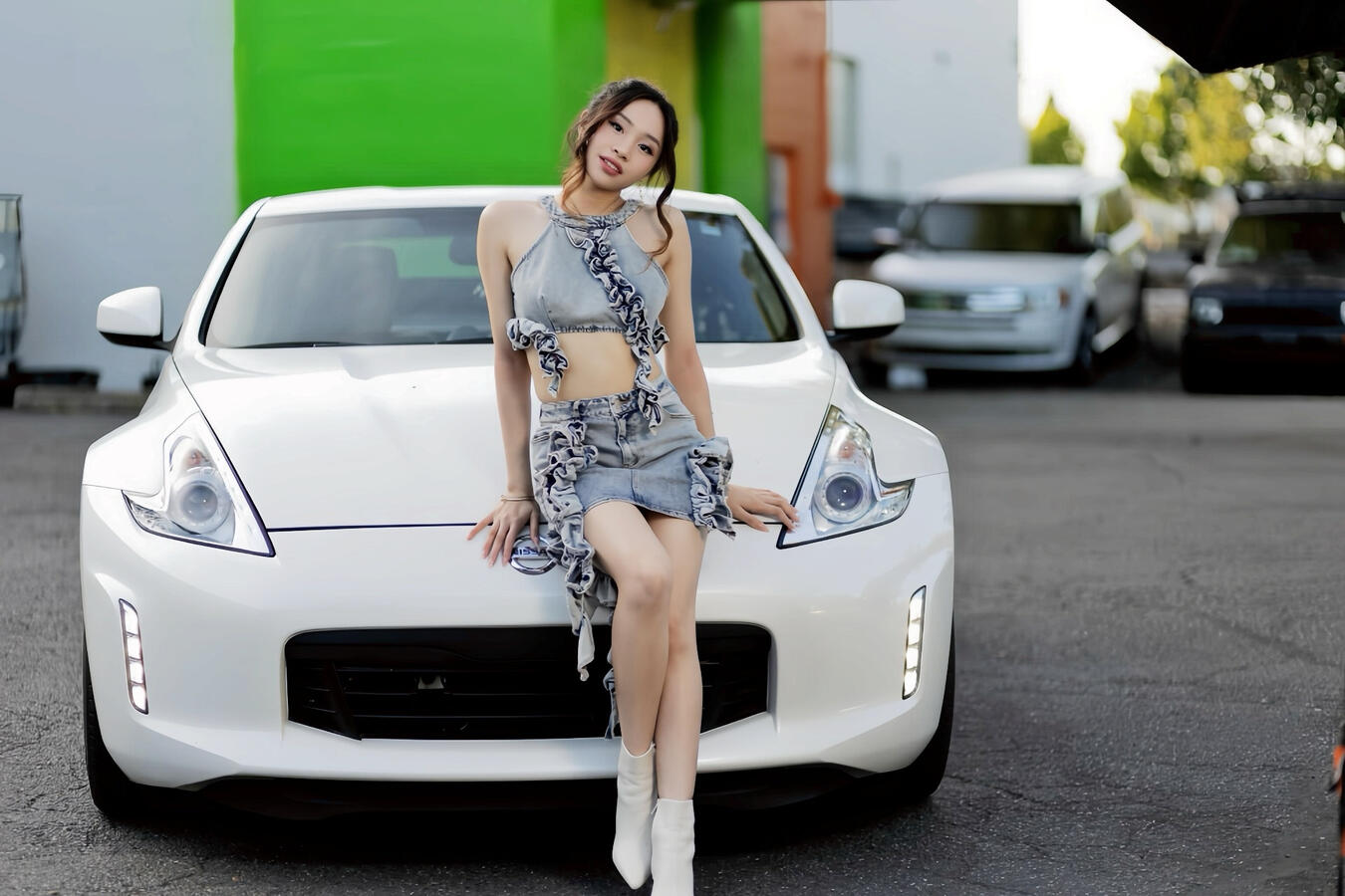Angeli Chaves smiling while sitting on a white Nissan 370Z in a denim ruffle outfit