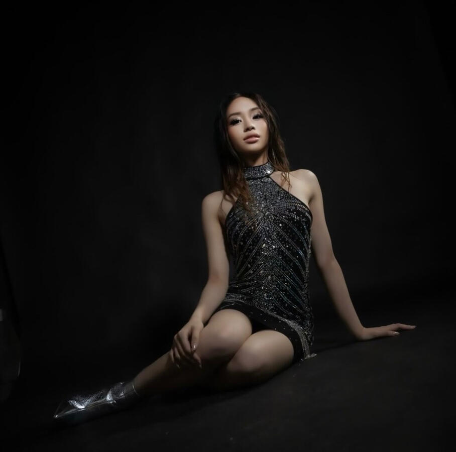 Angeli Chaves in red high-slit gown posing in front of evergreens for Kantana Magazine cover shoot