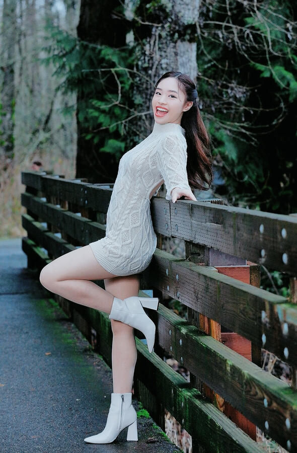 Angeli Chaves leaning on bridge in cream sweater and boots for Kantana Magazine photoshoot