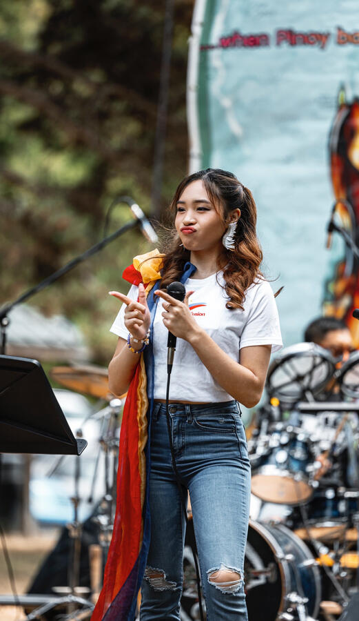 Angeli Chaves holding microphone on stage at Pista sa Nayon Seattle outdoor music event