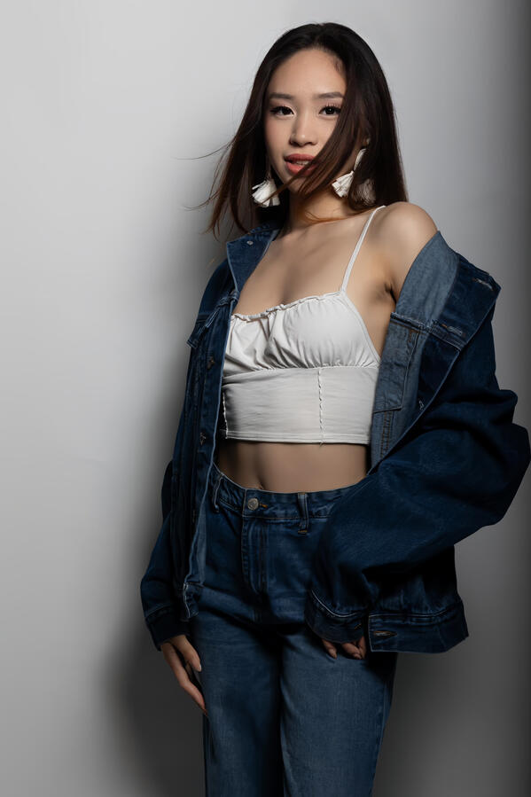 Angeli Chaves in a white crop top and oversized denim jacket with matching jeans