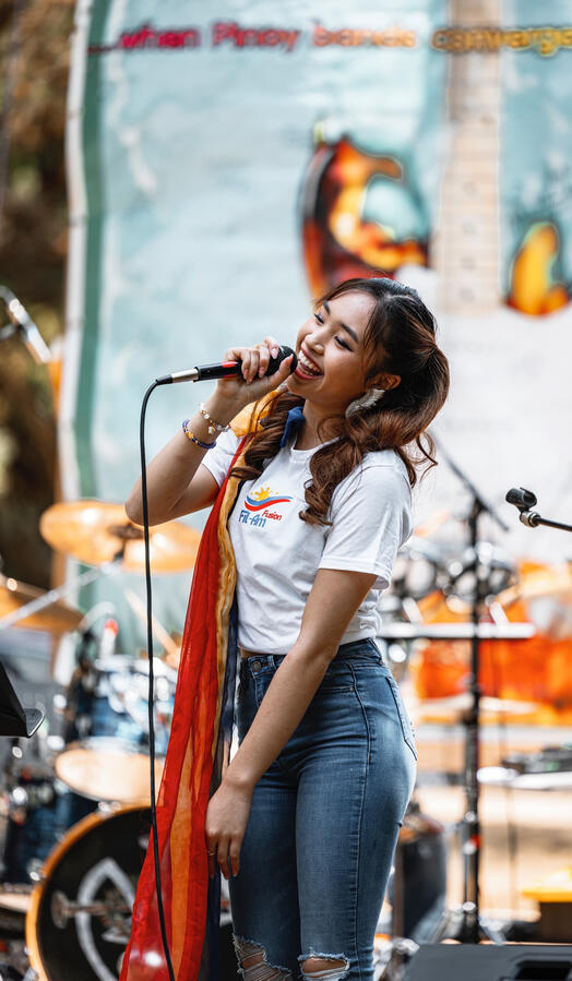 Angeli Chaves singing at Pista sa Nayon Seattle in white tee and jeans with live band